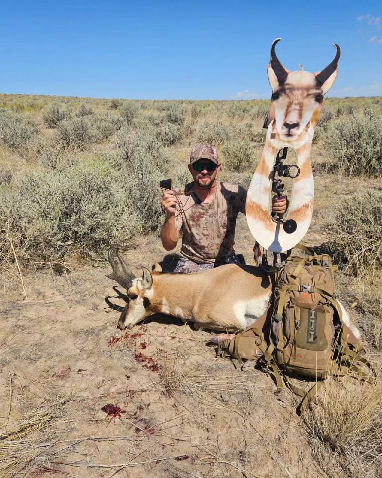 Hunter kneeling with harvested pronghorn and gear