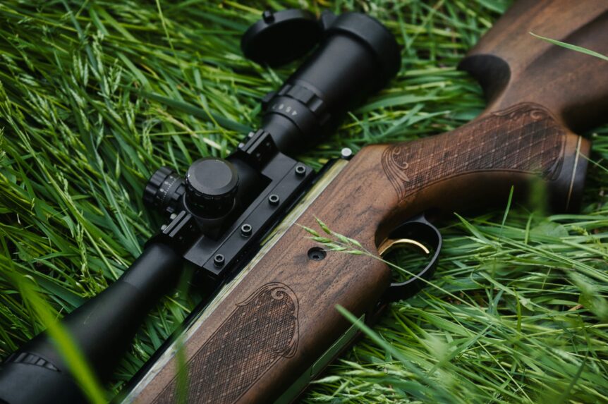 Wooden hunting rifle with scope lying in grass