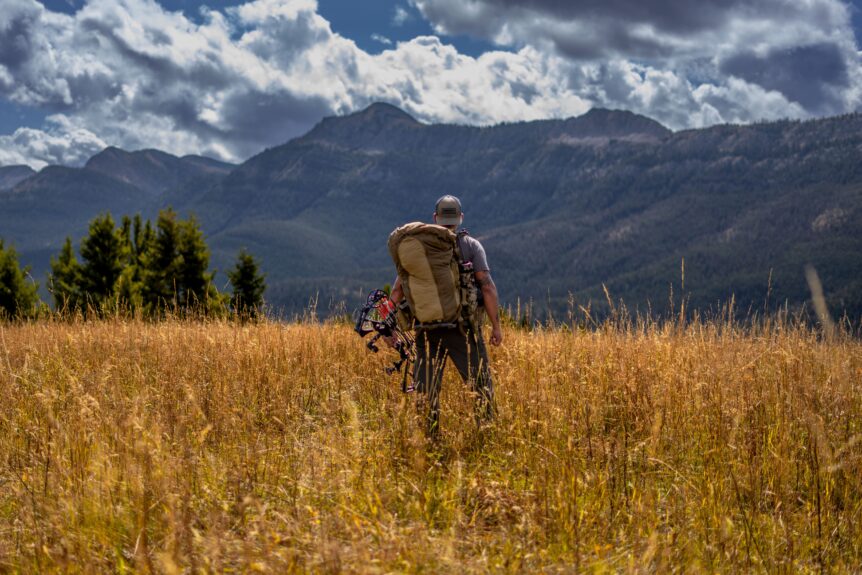 Hiker with backpack in grassy mountain meadow